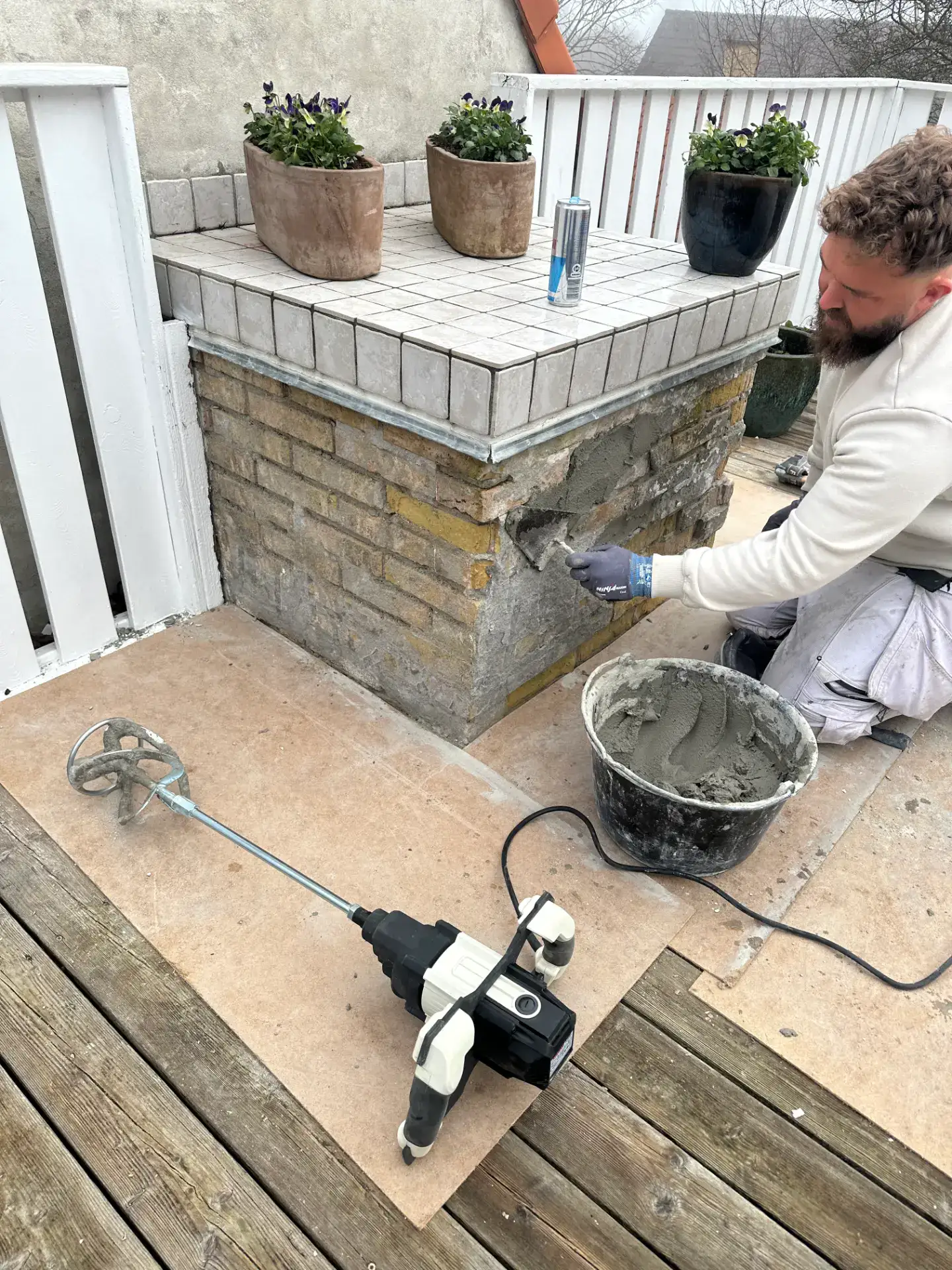 Murer arbejder på facade med mursten og cement, professionel håndværker i aktion.